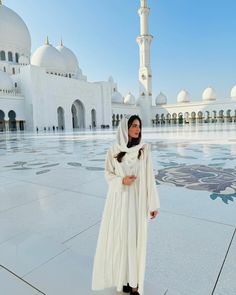 a woman standing in front of a large white building with many arches and domes on it