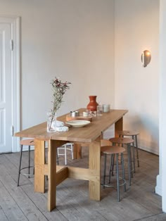 a wooden table with chairs around it and a vase on the table next to it