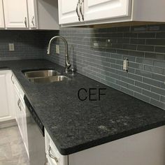 a kitchen with white cabinets and black granite counter tops in front of a stainless steel dishwasher