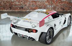 a white race car parked in front of a brick wall