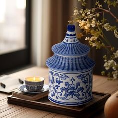 a blue and white tea pot sitting on top of a wooden tray next to a cup