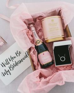 a pink gift box filled with champagne and personalized items for the bride to be