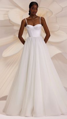 a woman in a white wedding dress standing with her hands on her hips