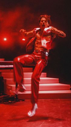 the man is dancing on stage in red pants