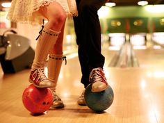 a man and woman are standing next to each other on the bowling ball in front of them