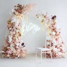 a white chair sitting in front of a flower covered arch with the word always on it