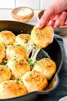 a person is sprinkling cheese on top of some rolls in a skillet