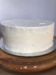 a white frosted cake sitting on top of a wooden table