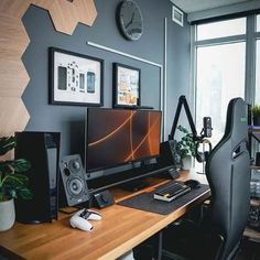 a desk with a computer and speakers on it in front of a wall mounted clock