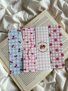 four bookmarks with cherries on them sitting on top of an open bookshelf