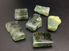 some green rocks sitting on top of a black table with one rock in the middle