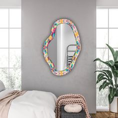 a mirror on the wall above a bed in a room with a chair and plant