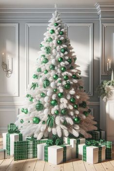 a white christmas tree with green ornaments and presents on the floor in front of it