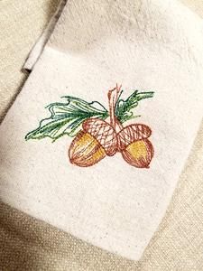 an embroidered piece of cloth with oranges on it and green leaves in the center