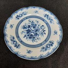 a blue and white plate sitting on top of a carpeted floor next to a wall