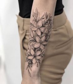 a woman's arm with flowers on it and a black ink tattoo in the middle