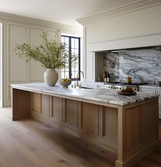 a large kitchen with marble counter tops and wooden cabinets, along with two vases on the island