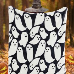 a black and white blanket with ghost faces on it in front of some pumpkins