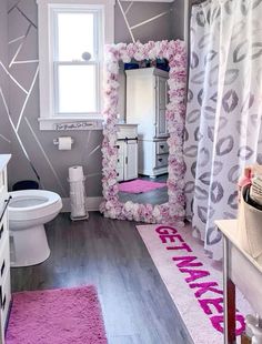 a bathroom decorated in pink and gray with flowers