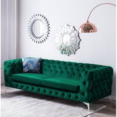 a green couch in a living room with mirrors on the wall and a lamp next to it