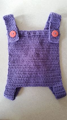 a purple crocheted baby bib with orange buttons