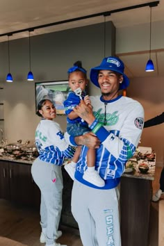 a man holding a child in his arms while standing next to two other people wearing matching outfits