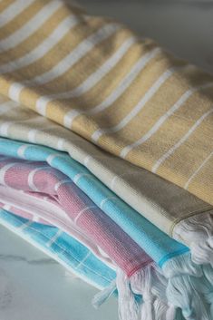 three towels folded on top of each other in different colors and patterns, sitting on a marble surface