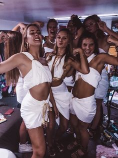 several women in white outfits posing for the camera