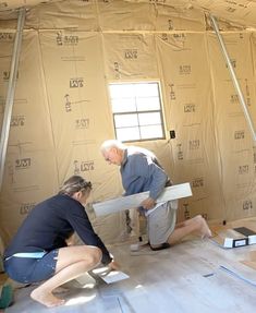 two people are working on the walls of a house that is being built in order to make it look bigger