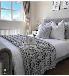 a bed with white sheets and pillows in a bedroom next to two framed pictures on the wall