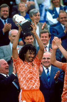 two men holding up a trophy in front of a crowd