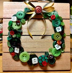 a close up of a wreath made out of buttons on a wooden board with a ribbon