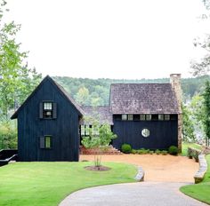 a large black house sitting on top of a lush green field