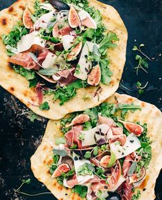 two pita breads topped with meat and veggies on a black surface