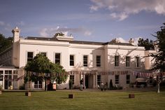 a large white building with flags hanging from it's roof and lawn in front