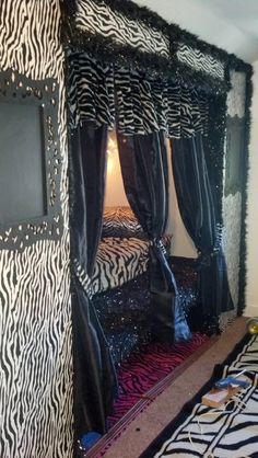 a zebra print canopy bed with black and white decor on the walls, in a bedroom