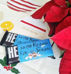 some candy bars sitting on top of a table next to red flowers and christmas decorations