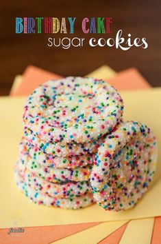 a stack of sprinkle covered cookies sitting on top of a yellow tablecloth