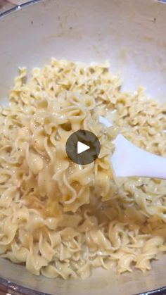 a bowl filled with noodles and sauce being stirred by a spatula to stir it