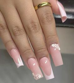 a woman's hand with pink and white manies on it, holding a gold ring