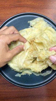 someone is peeling food on a black plate