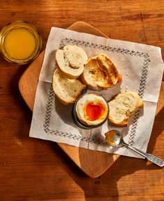 bread, jam and butter on a cutting board next to a glass of orange juice