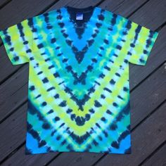 a blue and yellow tie - dyed t - shirt sitting on top of a wooden floor