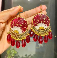 These handmade resin earrings feature a vibrant red base with original white flower, complemented by gold-tone metal and dangling beads. Perfect for adding a boho-chic touch to bright outfit. Handmade Red Flower Earrings For Festive Occasions, Red Flower Shaped Festive Jewelry, Red Flower-shaped Festive Jewelry, Festive Red Flower Earrings, Red Resin Round Jewelry, Red Round Resin Jewelry, Red Drop Flower Earrings For Festive Occasions, Festive Red Flower Drop Earrings, Red Resin Drop Earrings