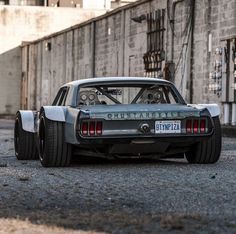 an old car is parked on the street in front of a brick wall and building