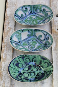 three blue and green plates sitting on top of a wooden table