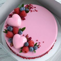 a heart shaped cake with raspberries and blueberries on top