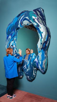 two people standing in front of a blue and white sculpture