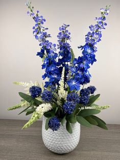 a white vase filled with blue and white flowers