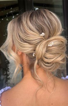 a woman with blonde hair in a low updo and some pearls on her head